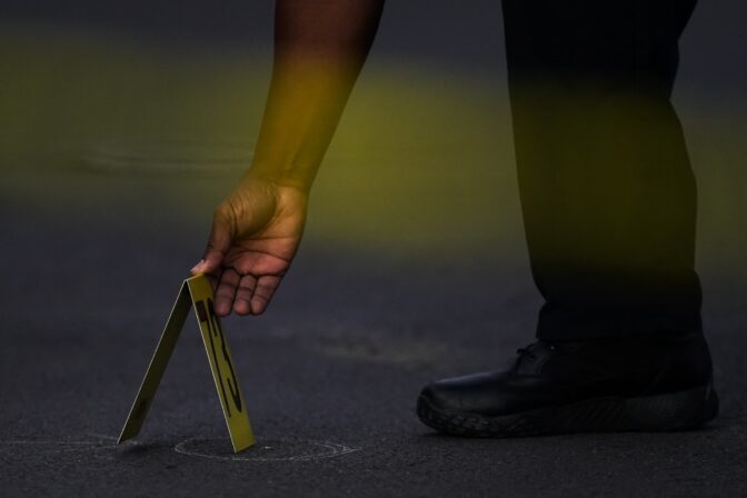 A police officer places an evidence marker at the scene where multiple people were shot near a high school in Philadelphia, Tuesday, Sept. 27, 2022.