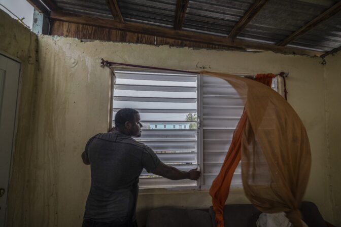 Nelson Cirino secures the windows of his home as the winds of Hurricane Fiona blow in Loiza, Puerto Rico, Sunday, Sept. 18, 2022.