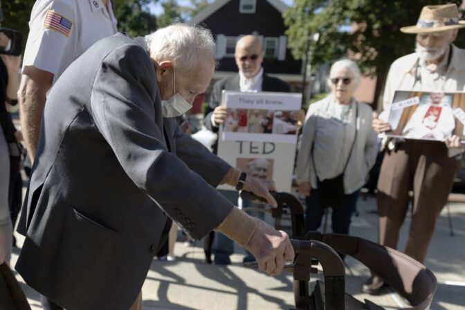 Demonstrators watch as former Cardinal Theodore McCarrick leaves Dedham District Court after his arraignment, Friday, Sept. 3, 2021, in Dedham, Mass.
