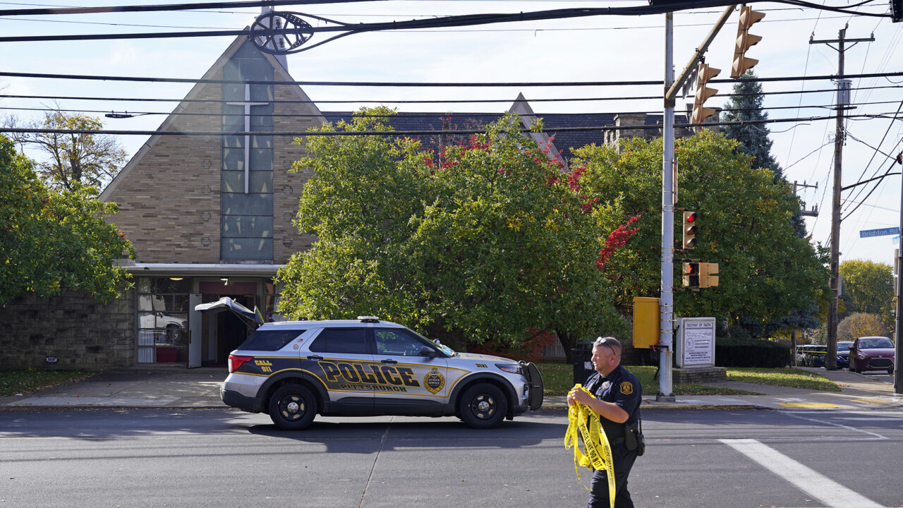 A Pittsburgh Police officer removes the Police Line barrier from around the scene outside the Destiny of Faith Church in Pittsburgh,