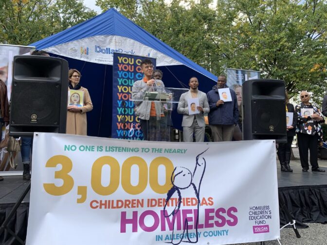 Michael, center, a former recipient of scholarships from the Homeless Children's Education Fund shares his story Tuesday during a demonstration in Market Square.