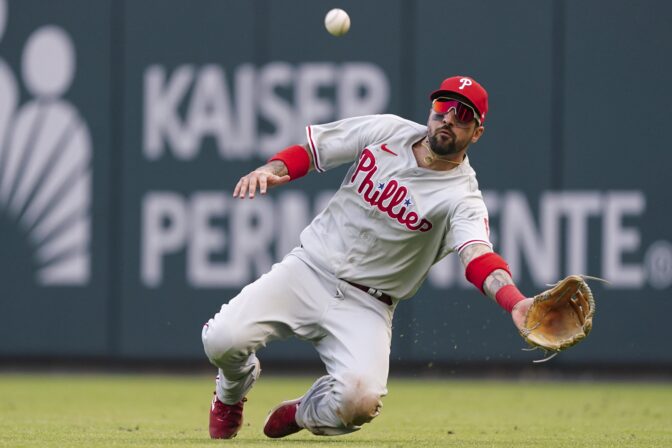 Philadelphia Phillies right fielder Nick Castellanos (8) makes a diving catch against Atlanta Braves catcher William Contreras during the ninth inning in Game 1 of a National League Division Series baseball game, Tuesday, Oct. 11, 2022, in Atlanta.