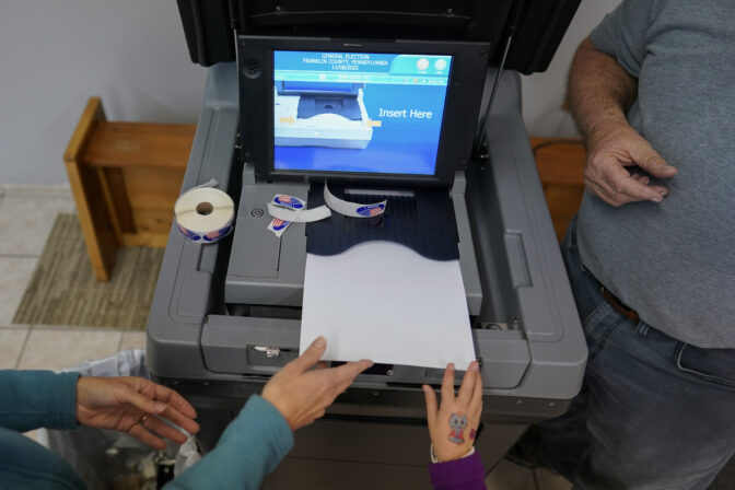 FILE - A voter and her daughter feed her ballot face down into a voting machine at the New LIFE Worship Center Church of God in Fayetteville, Pa., Tuesday, Nov. 8, 2022. On Friday, Nov. 11, The Associated Press reported on stories circulating online incorrectly claiming a Pennsylvania judge ruled that ballots received up until Nov. 14 will count in the 2022 midterm elections.