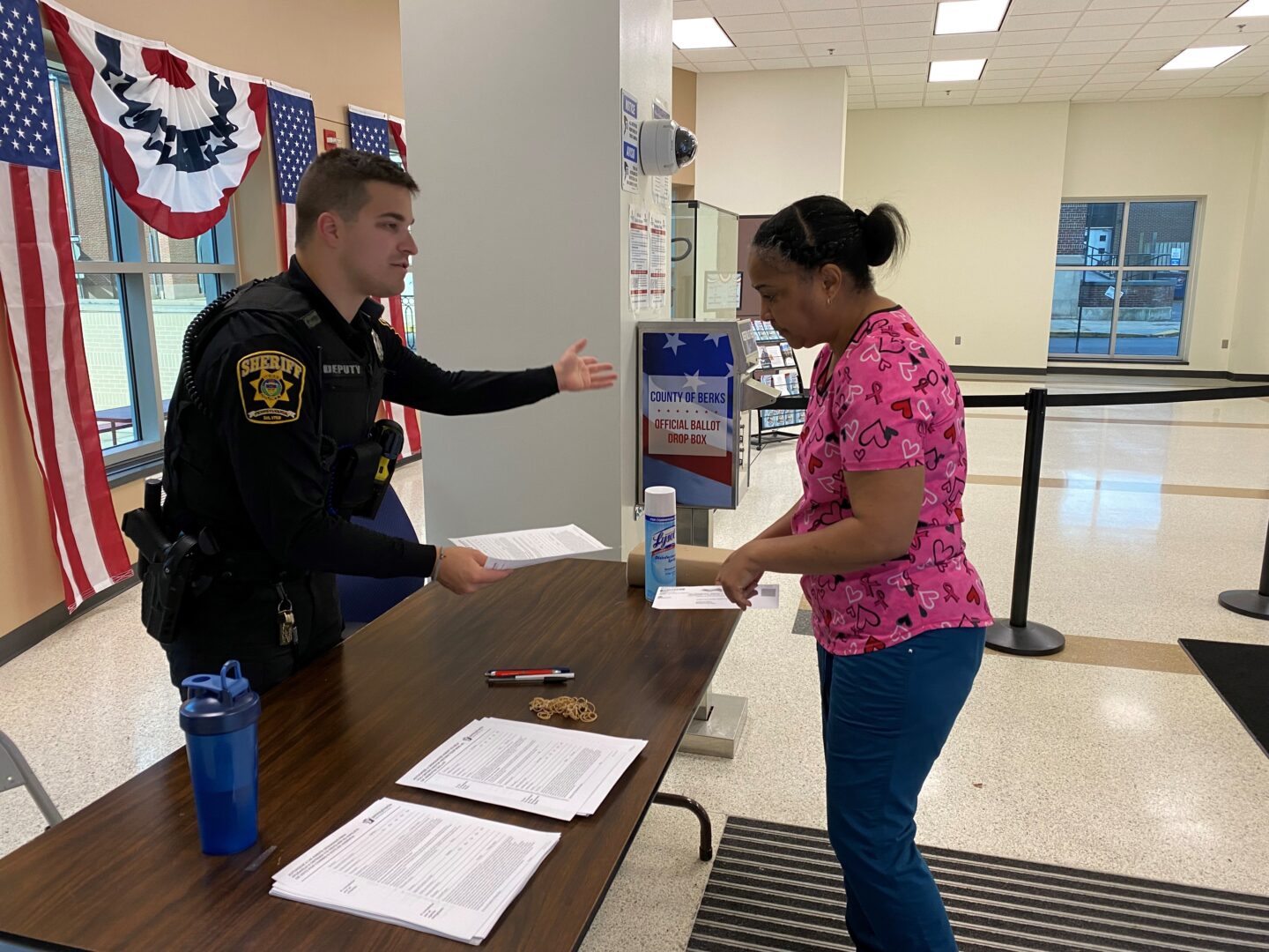 Berks County Deputy Sheriff Riley Gutierrez tells caretaker Lis Mejia that she will have to fill out a form to drop off the ballot for her client, 78-year-old Leonor McCoroy.