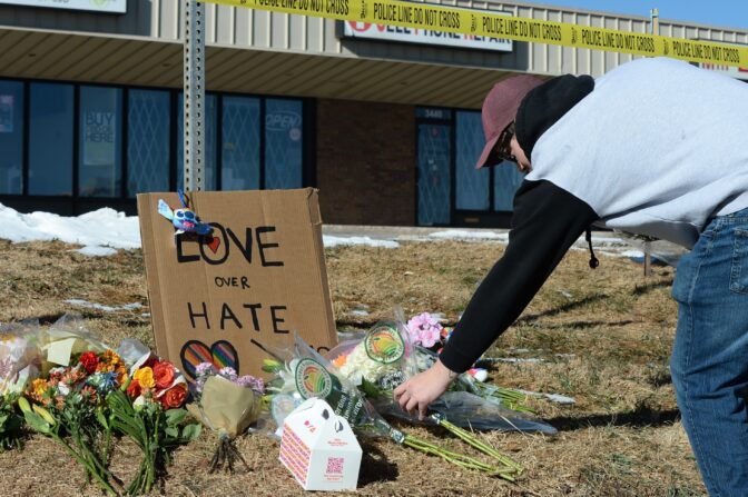 Elijah Newcomb of Colorado Springs lays flowers near a gay nightclub in Colorado Springs, Colo., Sunday, Nov. 20, 2022 where a shooting occurred late Saturday night.