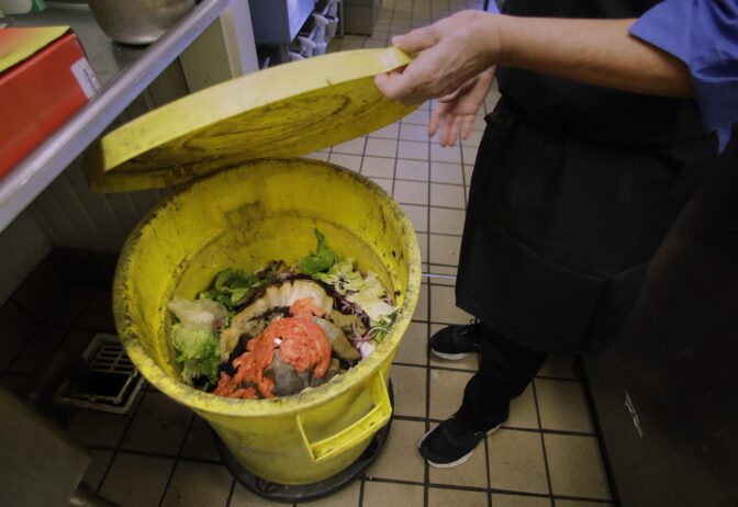 In this Thursday Oct. 19, 2017 photograph, Jane Calef, a supervisor at the UNH Dairy Bar, shows a vegetable composting bucket filled with lunchtime scraps at the University of New Hampshire, in Durham, N.H.