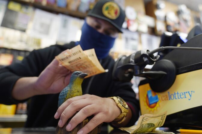 Store clerk Eduardo Duran rubs purchased lottery tickets on the head of the store lucky bluebird for the drawing of the Powerball lottery at the Blue Bird Liquor store in Hawthorne, Calif., Monday, Oct. 31, 2022.
