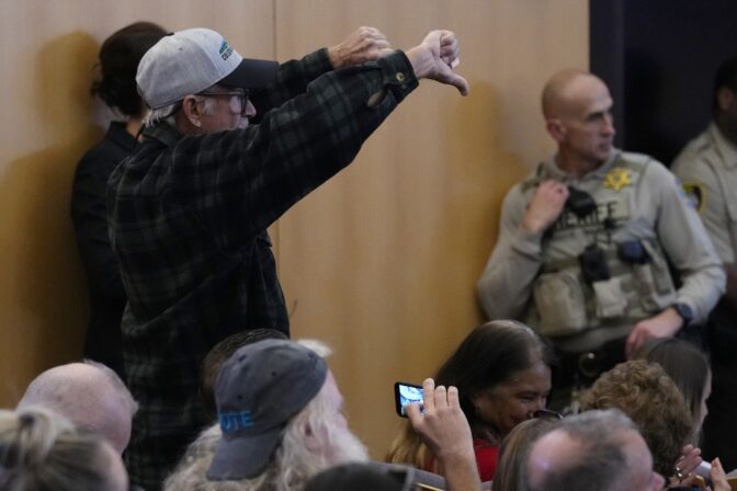 A man gives the thumbs down to the Maricopa County Board of Supervisors during their general election canvass meeting, Nov. 28, 2022, in Phoenix.