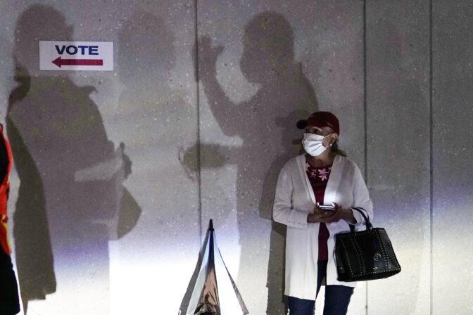 In this Oct. 19, 2020, file photo a woman waits to vote in Miami. Election officials are on high alert amid fears that U.S. polling stations could attract the same strain of partisan violence and civil unrest that erupted on American streets this year.