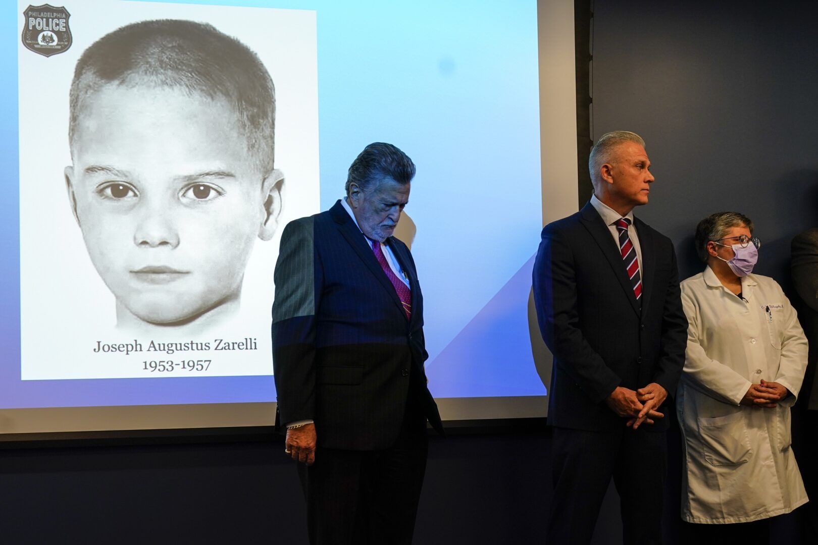 William C. Fleisher, with the Vidocq Society, center, Philadelphia Police Captain Jason Smith, and Dr. Constance DiAngelo, Philadelphia Chief Medical Examiner, listen during during a news conference in Philadelphia, Thursday, Dec. 8, 2022.