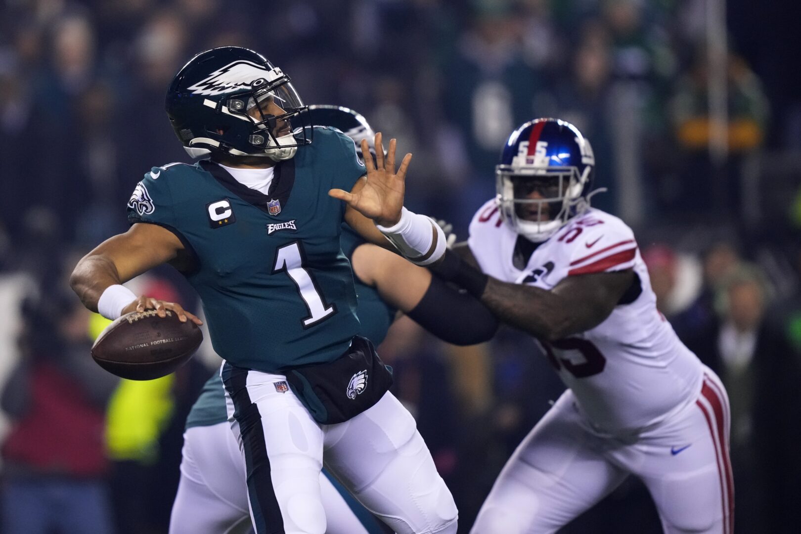 Philadelphia Eagles quarterback Jalen Hurts (1) throws a pass as New York Giants linebacker Jihad Ward (55) tries to rush in on him during the first half of an NFL divisional round playoff football game, Saturday, Jan. 21, 2023, in Philadelphia. (AP Photo/Matt Rourke)