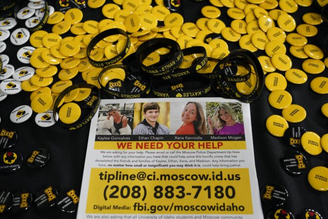 A flyer seeking information about the killings of four University of Idaho students who were found dead is displayed on a table along with buttons and bracelets on Nov. 30, 2022, during a vigil in memory of the victims in Moscow, Idaho.