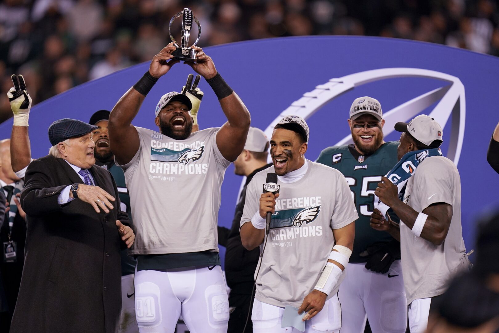 Terry Bradshaw, left, reacts as Philadelphia Eagles defensive tackle Fletcher Cox, second from left, hoists the George Halas Trophy as quarterback Jalen Hurts, center, holds a microphone after the NFC Championship NFL football game between the Philadelphia Eagles and the San Francisco 49ers on Sunday, Jan. 29, 2023, in Philadelphia. The Eagles won 31-7. 