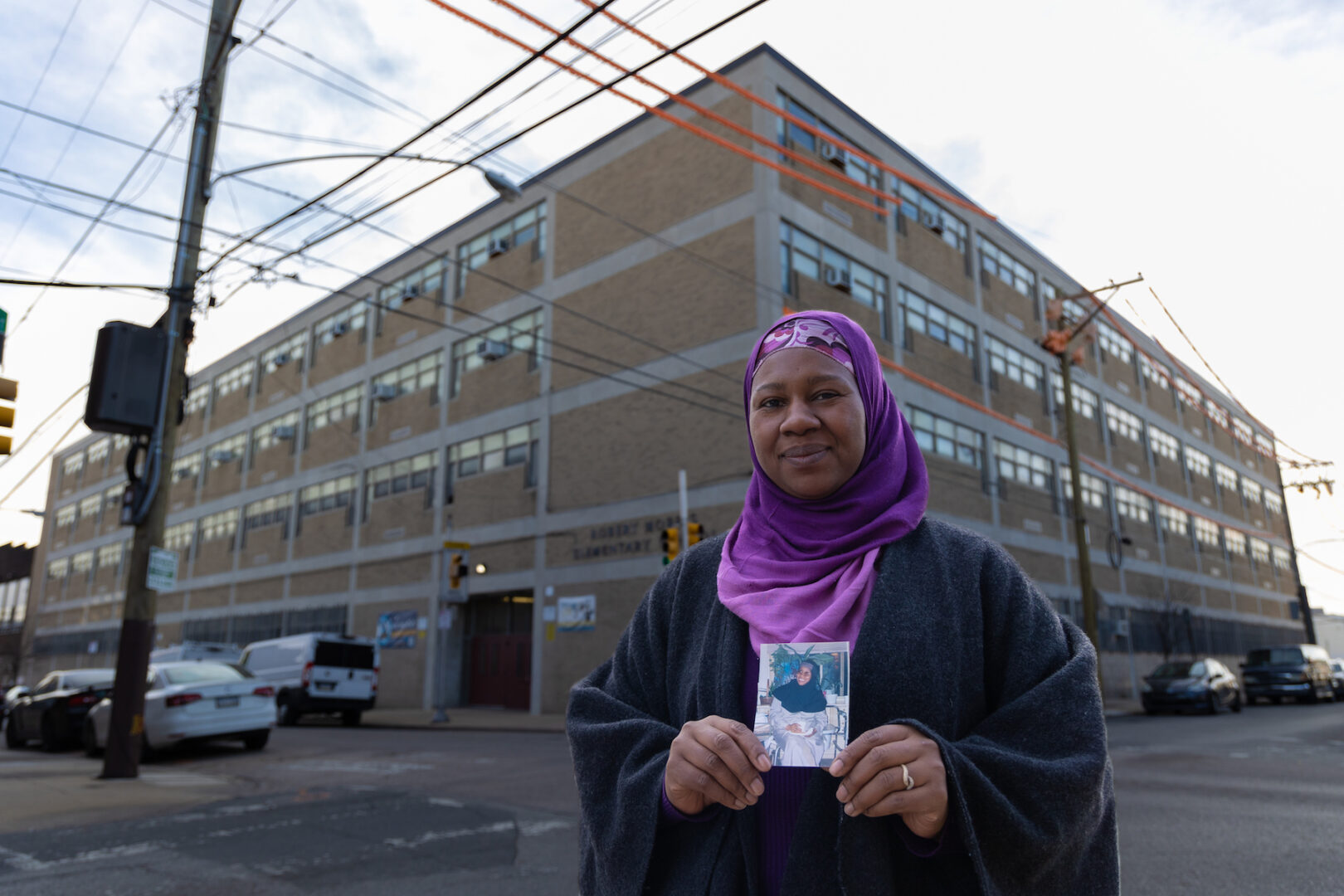 Haajar Aziz holds a photo of her mother, Aisha Elmekki outside Robert Morris Elementary School in Philadelphia. 