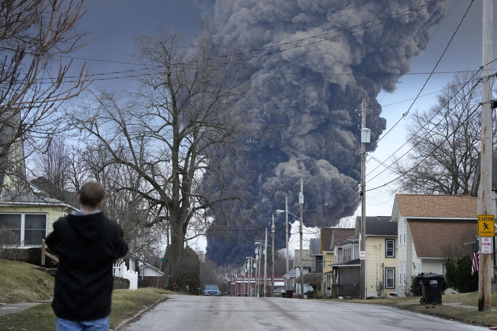 A man takes photos as a black plume rises over East Palestine, Ohio, as a result of a controlled detonation of a portion of the derailed Norfolk Southern trains Monday, Feb. 6, 2023. 