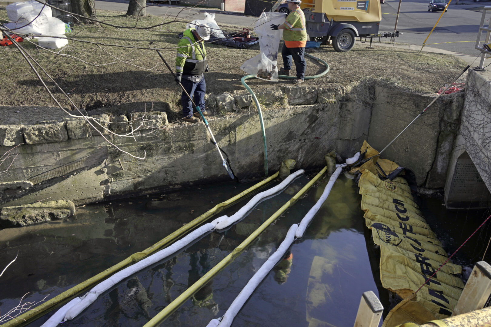 Booms are placed in a stream that flows through the center of East Palestine, Ohio, Wednesday, Feb. 15, 2023, as cleanup continues following the derailment of a Norfolk Southern freight train over a week ago. 