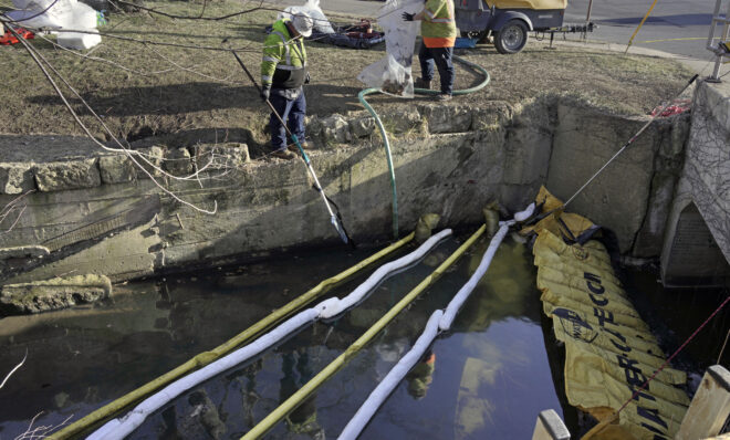 Booms are placed in a stream that flows through the center of East Palestine, Ohio, Wednesday, Feb. 15, 2023, as cleanup continues following the derailment of a Norfolk Southern freight train over a week ago. 