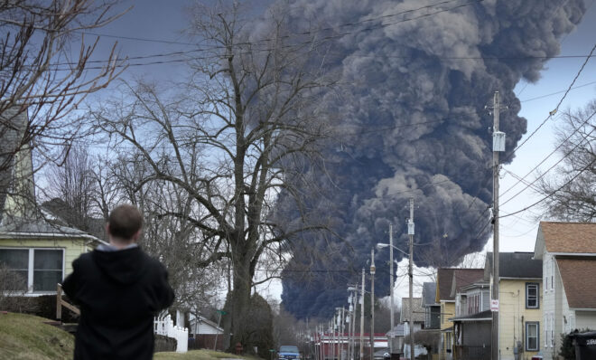 A man takes photos as a black plume rises over East Palestine, Ohio, as a result of a controlled detonation of a portion of the derailed Norfolk Southern trains Monday, Feb. 6, 2023. 