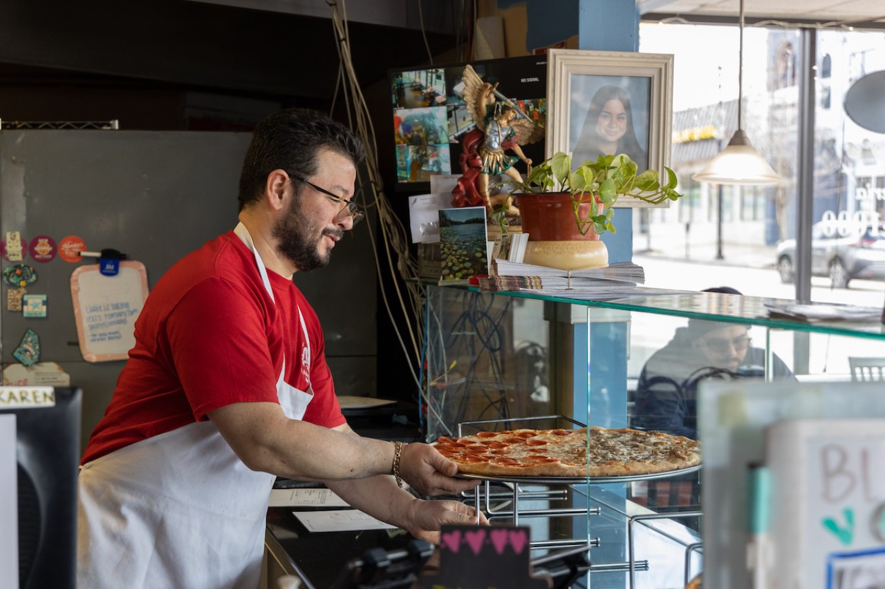 Owner Omar Quiñonez puts a pizza in the display case around lunch time at Amy’s Pizzeria. 
