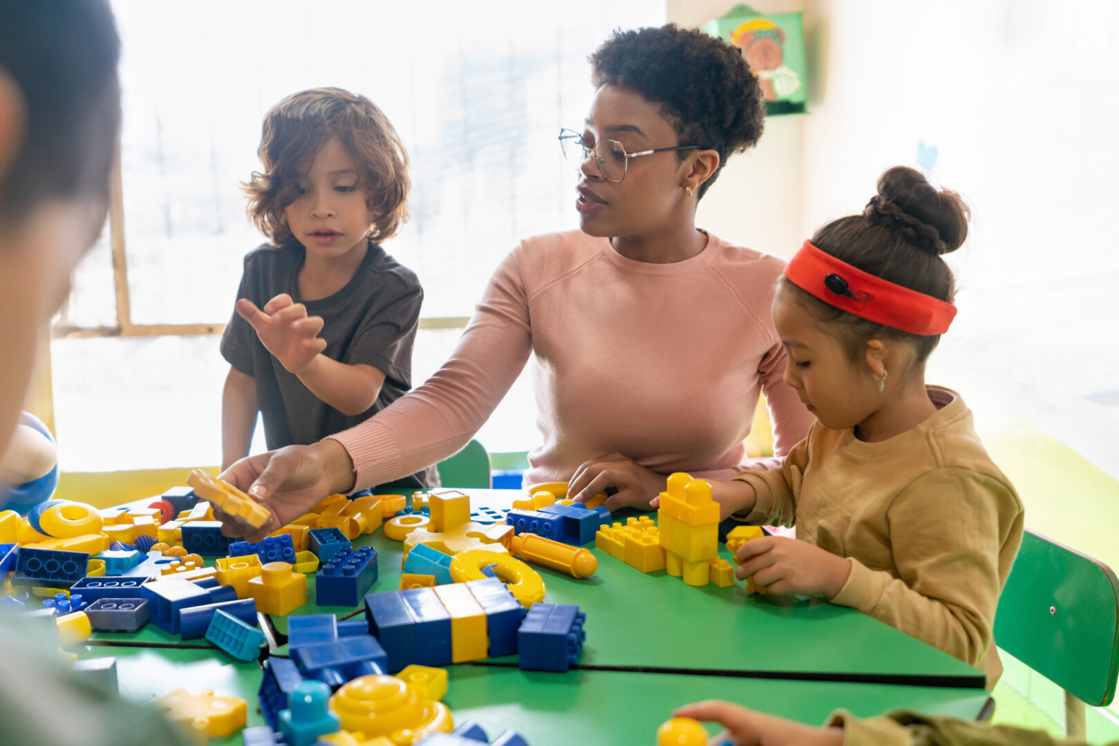 African American teacher playing with toy blocks in class at the school - education concepts
