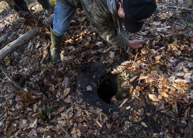 Joe Thomas clears leaves from an abandoned well on the Duke Center, Pa. property he and his wife, Cheryl, own.