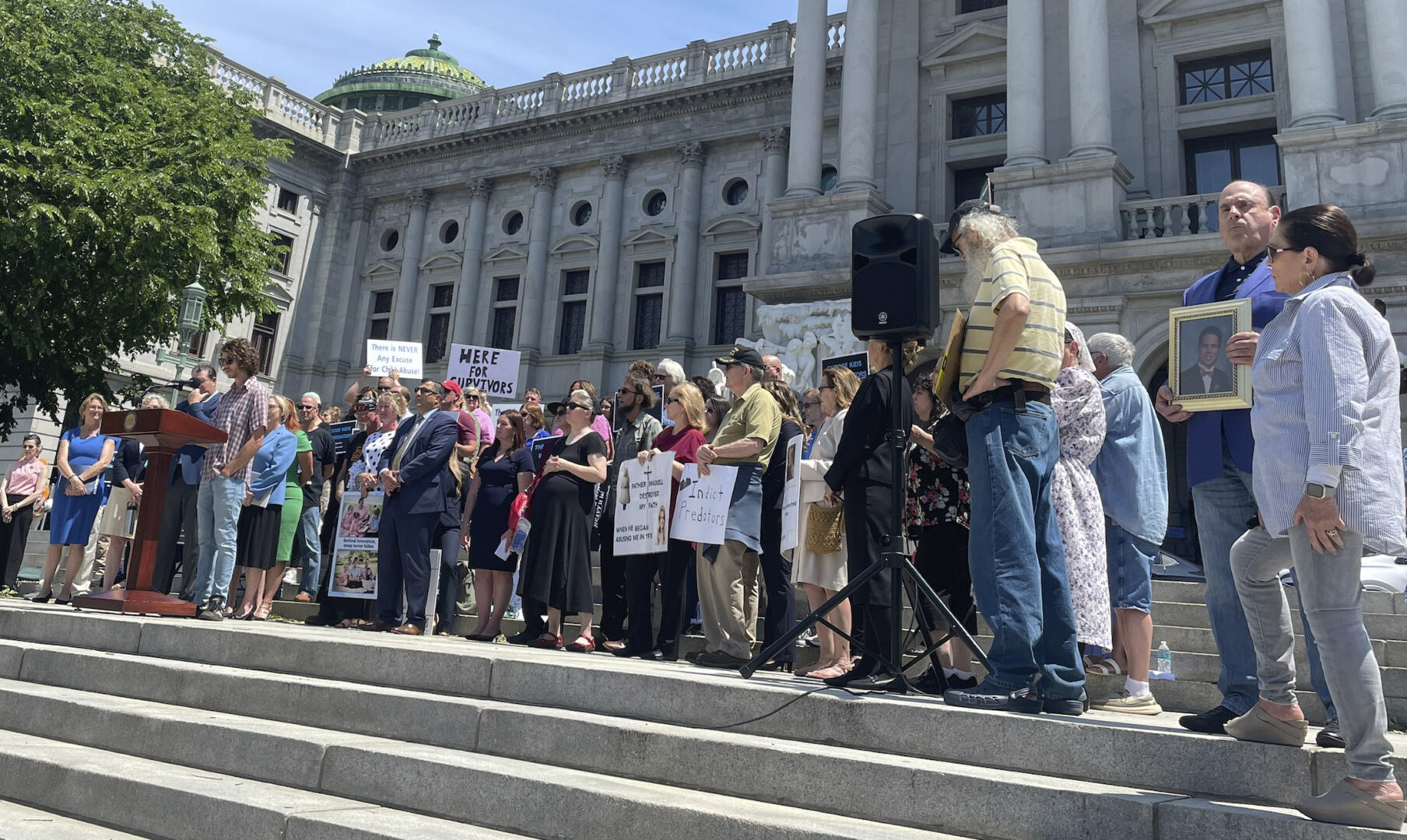 Caleb Kauffman, at podium, speaks at a rally outside of the Pennsylvania state Capitol in Harrisburg, Pa., June 5, 2023. Kauffman, a survivor and advocate, and others were calling on the state Senate to pass two pieces of legislation that would open a two-year window for child sex abuse survivors to file otherwise outdated lawsuits over their claim.