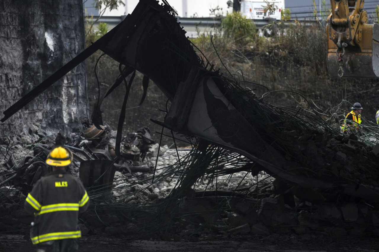 A firefighter views the aftermath of an elevated section of Interstate 95 that collapsed, in Philadelphia, Monday, June 12, 2023. Drivers began longer commutes after section of I-95 collapse a day earlier following damage caused by a tanker truck carrying flammable cargo catching fire. (AP Photo/Matt Rourke)