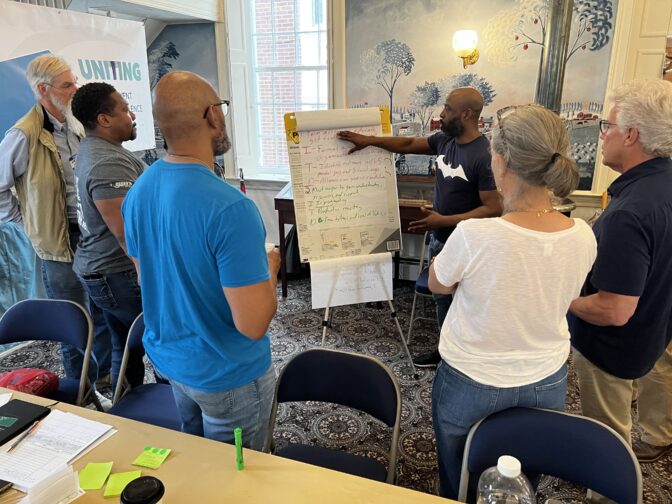 Group members with Uniting to Prevent Targeted Violence listen to a presentation during a meeting on May 13, 2023.