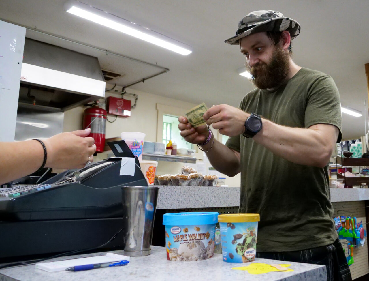 Alan "Legoman" Dwyer, 36, of New Hampshire pays for his half gallon of ice cream at the Pine Grove Furnace store on Tuesday, July 18, 2023.