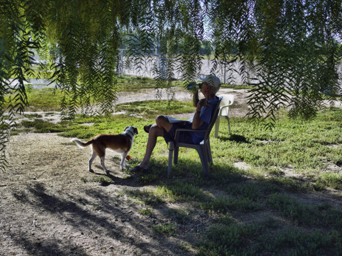 A man sits with his dog and hydrates in the shade in an attempt to beat the heat in Los Angeles on Thursday, July 13, 2023. After a historically wet winter and a cloudy spring, California's summer is in full swing. A heat wave that's been scorching much of the U.S. Southwest is bringing triple digit temperatures and an increased risk of wildfires.