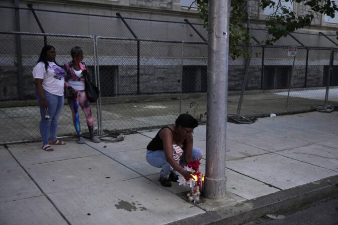 Stacy Satchell, right, lights a candle at a memorial for her nephew, DaJuan Brown, who died in Monday's fatal shooting spree, Wednesday, July 5, 2023, in Philadelphia.