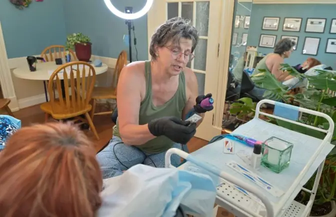 Barbara Fox, a restorative tattoo artist, preps her equipment before she starts work on Julie Swartz, to restore an areola after breast cancer on Thursday, June 1, 2023. Both women are breast cancer survivors, and after her battle, Fox decided to use her talents as an artist to become a restorative tattoo artist.
