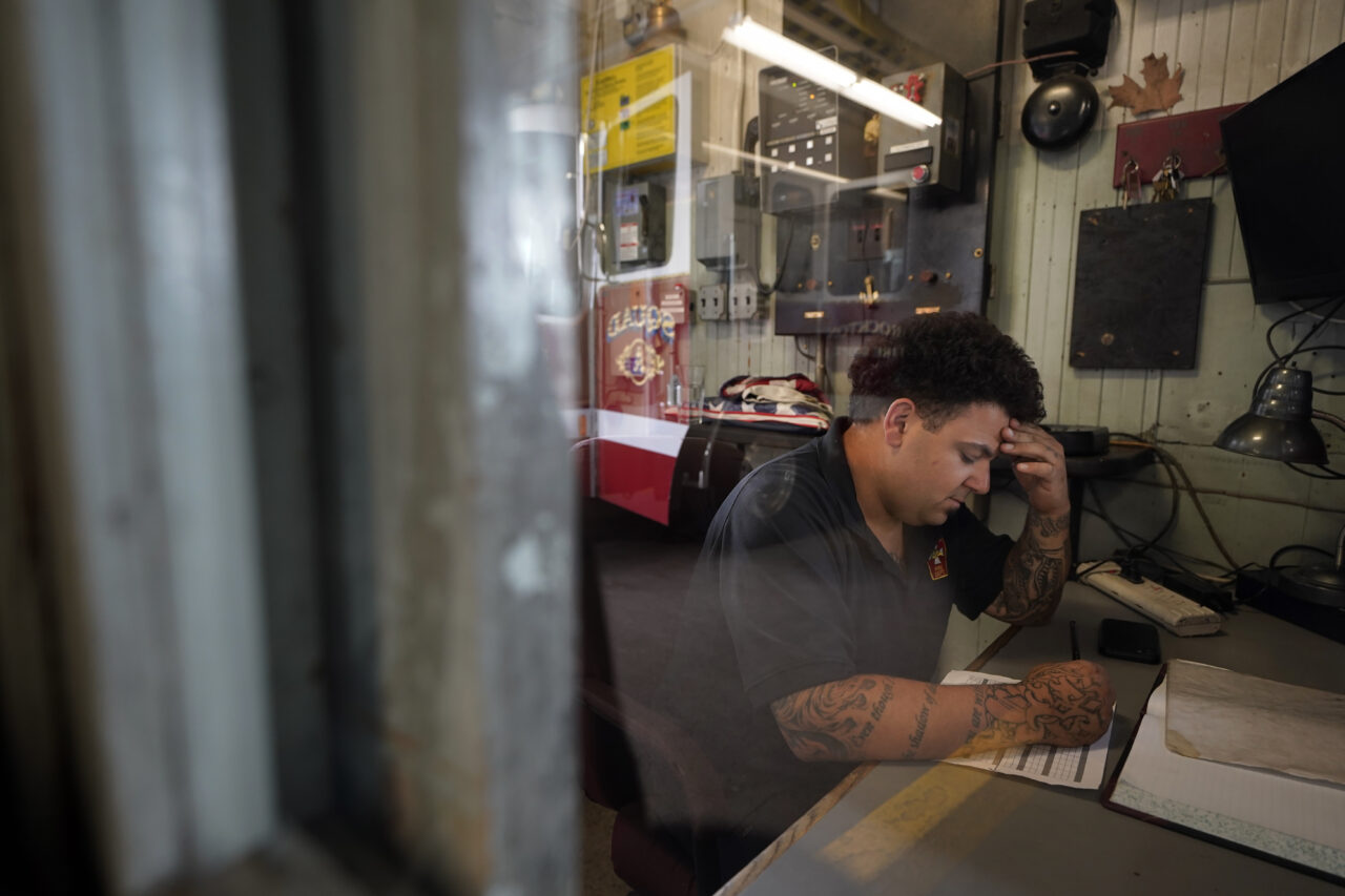 Brockton firefighter Tyler Palie works in the patrol booth at Station 1, Thursday, Aug. 3, 2023, in Brockton, Mass. Firefighters around the country are concerned that gear laced with the toxic industrial compound PFAS could be one reason why cancer rates among their ranks are rising. The chemical, which has been linked to health problems including several types of cancer, is used in turnout gear to repel water and other substances when fighting a fire. (AP Photo/Steven Senne)