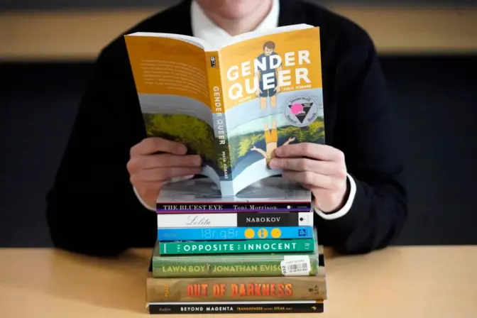 FILE - Amanda Darrow, director of youth, family and education programs at the Utah Pride Center, poses with books that have been the subject of complaints from parents on Dec. 16, 2021, in Salt Lake City. The nationwide surge in book bannings continues. The American Library Association reported Wednesday, Sept. 20, 2023, that challenges to books in schools and public libraries will likely reach record highs in 2023, topping what had been a record pace in 2022.