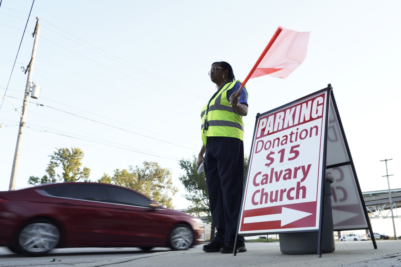 Lisa M. Lewis directs vehicles into the Calvary Baptist Church parking lot which is located near the Philadelphia Union's Subaru Park prior to a soccer game, Wednesday, Oct. 4, 2023, in Chester, Pa. The church raises up to $3,000 per game — about half of what goes into the collection plate on Sundays, said its pastor, Keith Dickens. (AP Photo/Michael Perez)
