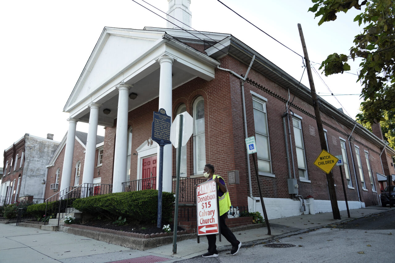 Karen Hull carries a parking sign at the Calvary Baptist Church parking lot which is located near the Philadelphia Union's Subaru Park, Wednesday, Oct. 4, 2023, in Chester, Pa. (AP Photo/Michael Perez)