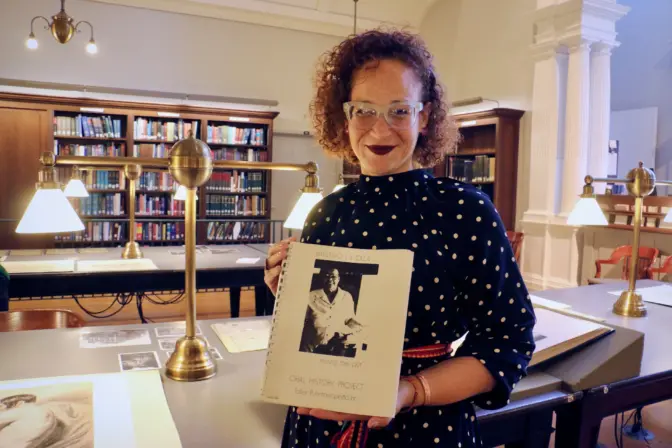Nasheli Juliana Ortiz-González, CEO of Taller Puertorriqueño, holds a transcript of Taller’s oral history project from the 1970s which is on display in the reading room of the Historical Society of Pennsylvania. (Emma Lee/WHYY)