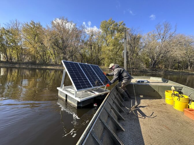 Minnesota Department of Natural Resources Fisheries Technician James Stone works to remove a floating solar-powered telemetry receiver from the Mississippi River backwaters near La Crosse, Wis. on Monday, Nov. 6, 2023. Multiple wildlife agencies have begun using the receivers to track tagged invasive carp in real time to learn the fish's movement patterns and launch capture operations. (AP Photo/Todd Richmond)