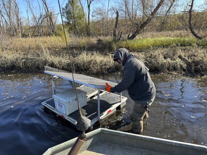 Minnesota Department of Natural Resources Fisheries Technician James Stone works to remove a floating solar-powered telemetry receiver from the Black River near LaCrosse, Wis. on Monday, Nov. 6, 2023. Multiple wildlife agencies have begun using the receivers to track tagged invasive carp in real time to learn the fish's movement patterns and launch capture operations. (AP Photo/Todd Richmond)
