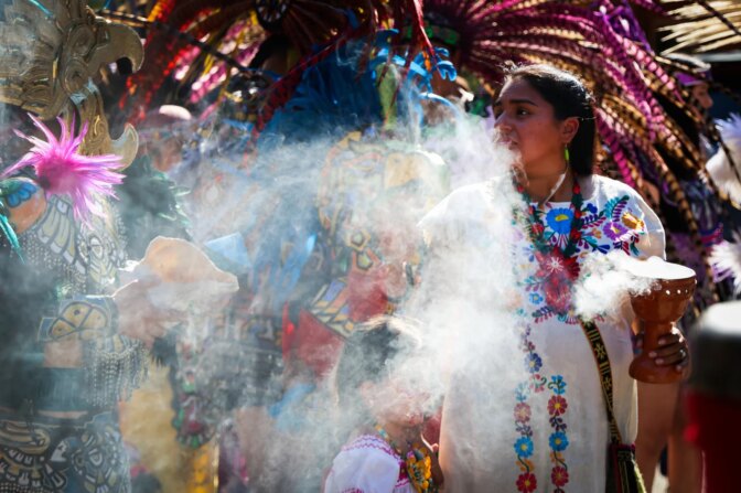 Members of the Mitotiliztli Yaoyollohtli Aztec dance company line up for the march for Santos Rodriguez 50th Anniversary Commemoration Sunday, July 23, 2023, Pike Park near downtown Dallas.