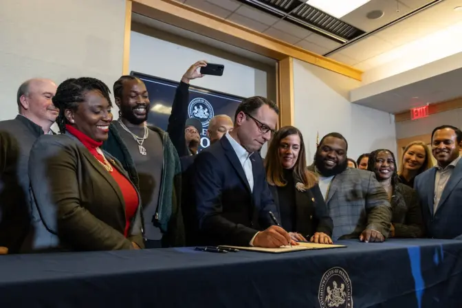 Pa. Governor Josh Shapiro signs justice reforms bill 898 into law surrounded by activists and other lawmakers at the National Constitution Center in Philadelphia on December 15, 2023. (Kimberly Paynter/WHYY)