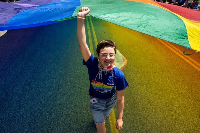Sophia Lewis, 13, of Maryland Heights, Mo., helps hoist a giant rainbow flag down Market Street on Sunday, June 25, 2023, during the St. Louis PrideFest Parade in downtown St. Louis.