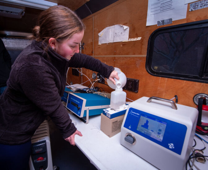 Keelie Steiner, a Millersville University undergraduate student, pours isopropyl alcohol into a scanning mobility particle sizer inside the Air Quality Monitoring Station for Millersville Atmospheric Research and Aerostat Facility on Monday, Dec. 4, 2023. The monitoring station is a trailer that’s parked behind the Farm & Home Center 1383 Arcadia Road to monitor air quality from Rt. 30 which runs behind the Farm & Home Center.