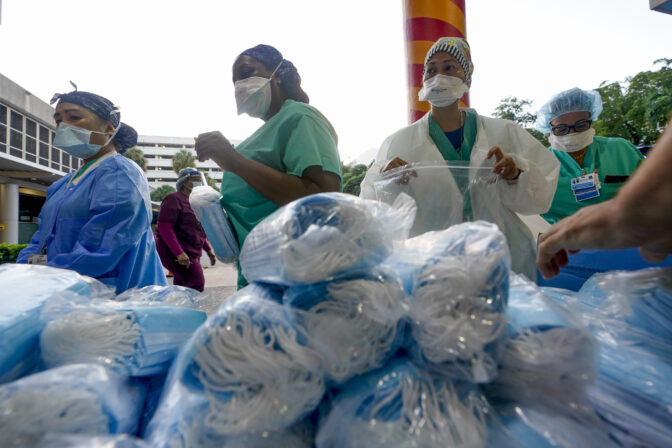 FILE - Healthcare workers line up for free personal protective equipment in front of murals by artist Romero Britto at Jackson Memorial Hospital, Tuesday, Sept. 22, 2020, in Miami. Some states that stockpiled millions of masks and other personal protective equipment during the coronavirus pandemic are now throwing the items away.(AP Photo/Wilfredo Lee, File)