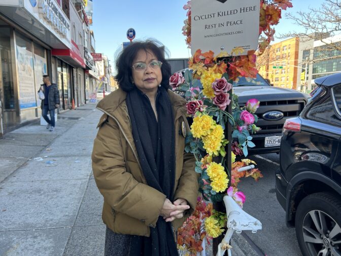 Lizi Rahman puts silk flowers on the white-painted "ghost" bicycle that marks the spot on Queens Boulevard where her son Asif was killed in 2008.