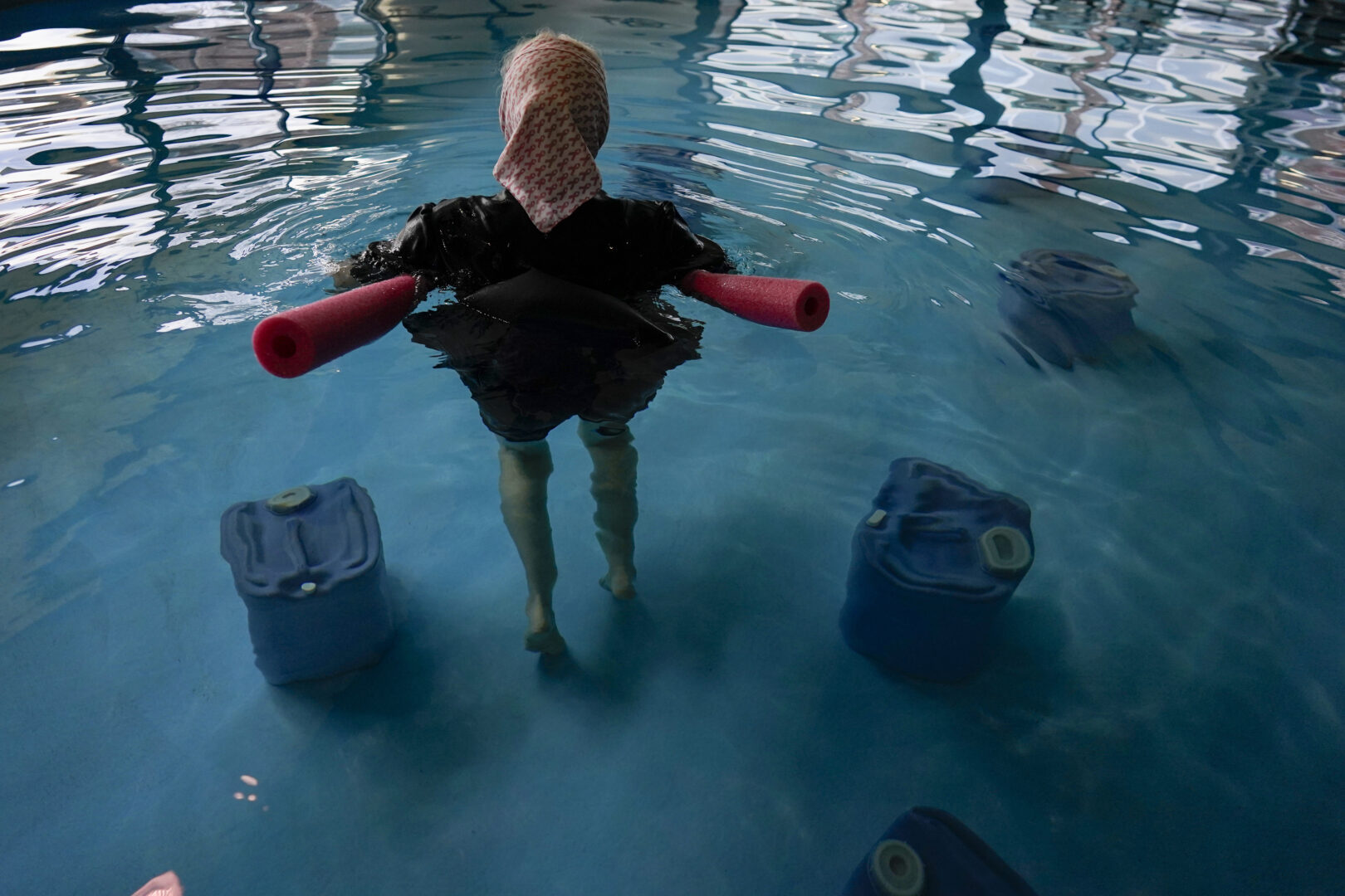 An Amish woman from Ohio floats with a pool noodle among BioHealing generators at the Tesla Wellness Hotel and MedBed Center on Wednesday, Nov. 15, 2023, in Butler, Pa. Tesla Biohealing — which has no connection to the car company — is part of a growth industry marketing unproven cures and treatments to conspiracy theorists and others who have grown distrustful of science and medicine. (AP Photo/Carolyn Kaster)