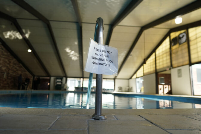 A sign that reads "Please do not move the swimming pool generator" is posted on the pool handrail at the Tesla Wellness Hotel and MedBed Center on Wednesday, Nov. 15, 2023, in Butler, Pa. The canisters contain a mix of “fine naturally active stones and activated fine metal, grout, sands and proprietary polymers that are manufactured with a special technology.” (AP Photo/Carolyn Kaster)