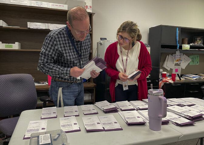 Election clerk Tony Phillips and election intern Maggie Bachman sort the mail ballots received on Election Day into precincts.