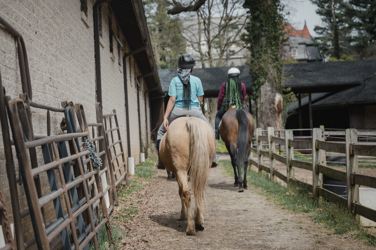 Jor’dyn Williams, 13, left, and Tajee McLaughlin, 14, ride their horses at the Northwestern Stables in Philadelphia, PA, on Saturday March 30 2024. Hannah Yoon for NPR