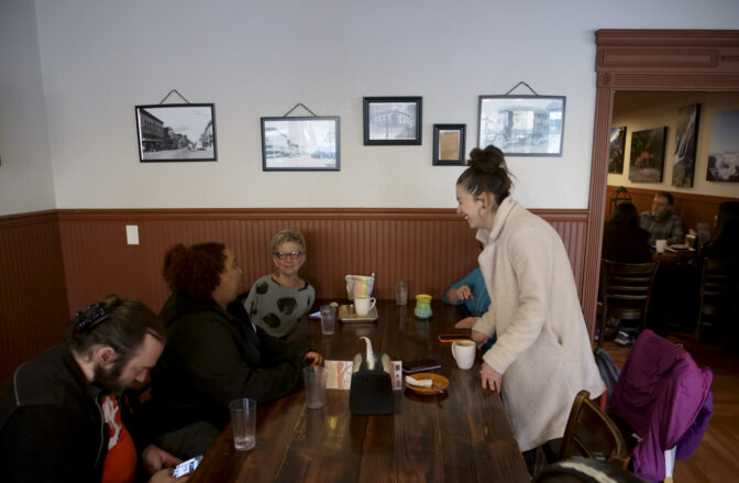 MacKenzie McGee, executive director of the Centralia Downtown Association (standing) chats with local business owners during coffee and breakfast at Dawn's Delectables pictured on March 8, 2024. (Jeremy Long - WITF)